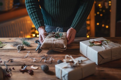 Close up of unrecognizable male hands wrapping Christmas gifts with natural materials.