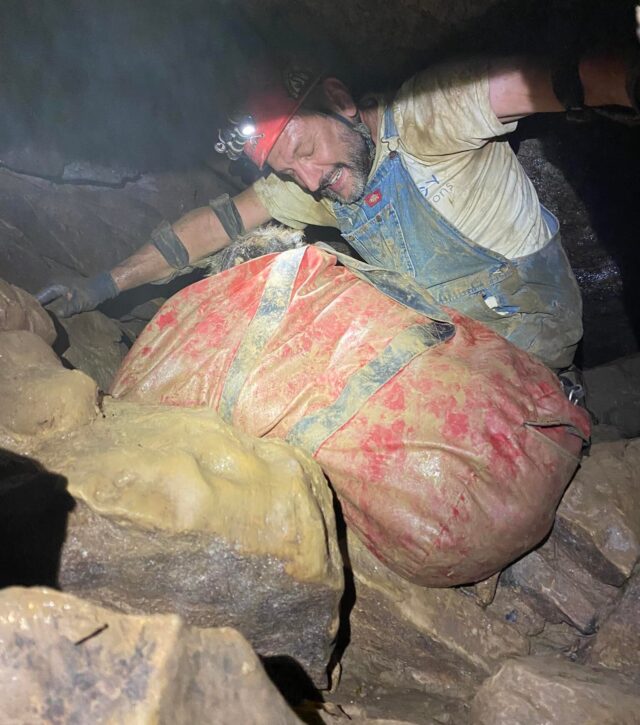 Man climbing out of cave with dog